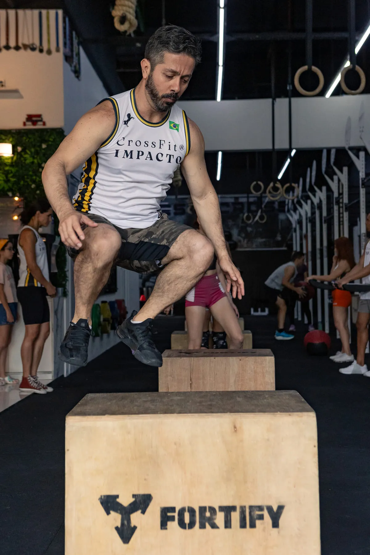 Atleta de regata do CrossFit Impacto no alto de um salto na caixa, durante a aula.